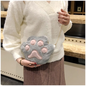 Close-up of plush grey cat paw bag with pink pads and gold chain shoulder strap