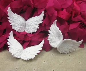 Detailed view of small white plastic angel wings with feather textures for DIY crafts