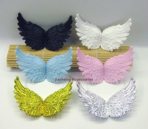 Macro detail of plastic angel wings set with embossed feather textures in multiple colors