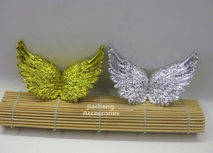 Detail view of gold and silver plastic angel wings with textured feather patterns for DIY