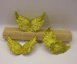 Close-up of golden angel wing crafts with detailed feather texture on bamboo mat