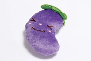 Detail of purple eggplant plush dog toy with embroidered face and green leaf top