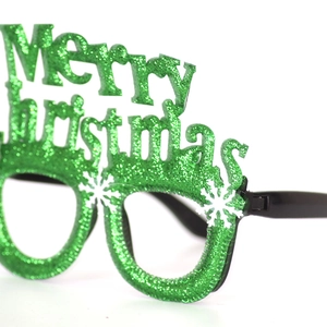 Detail of green sequin Merry Christmas glasses with white snowflake patterns