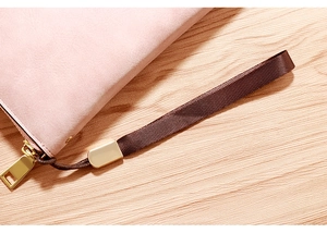 Close-up of pink faux leather wallet featuring a gold zipper and brown wrist strap