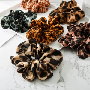 Set of six satin leopard print scrunchies in varied colors on a marble tabletop