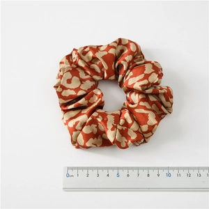 Leopard print satin scrunchie with a 10cm diameter measurement on a white background