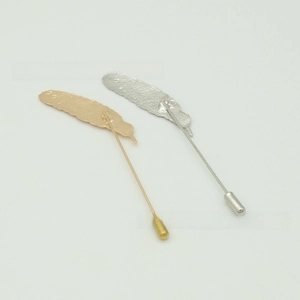 Detailed macro view of gold and silver feather lapel pins with protective caps for suits