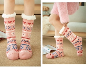 Close-up of pink Nordic style fleece-lined floor socks with white plush cuffs and heart patterns