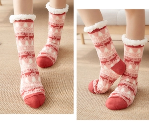 Detail of pink lamb wool floor socks with red reindeer pattern and anti-slip soles