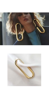 Detailed view of gold-plated geometric oval hoop earrings on silk and modeled lifestyle