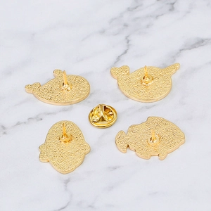 Set aus goldenen Emaille-Pins mit Wal- und Meeresschildkröten-Motiv auf weißem Marmor