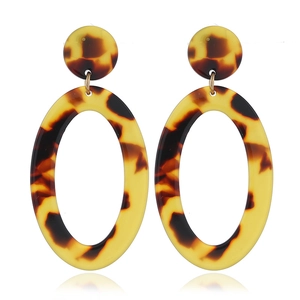 Detail of tortoise shell acrylic earrings with gold metal rings on white background