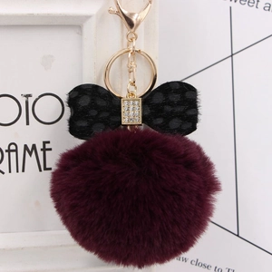 Macro detail of wine red faux fur pompom keychain with a black polka dot fabric bow
