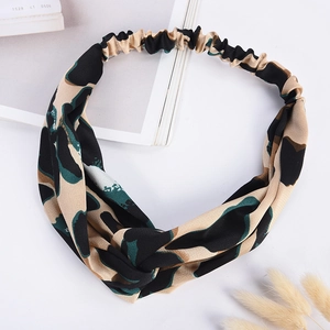 Detail view of elastic twist headband with beige and green leopard print on white background