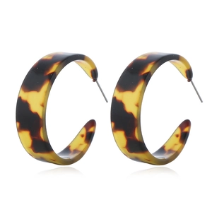 Detail view of C-shaped acetate hoop earrings showing classic tortoiseshell pattern textures
