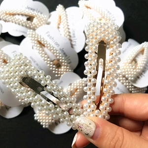 Close-up of elegant pearl hair clips with gold and silver metal frames held by hand