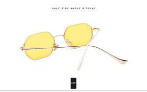 Detail view of gold octagonal sunglasses featuring yellow lenses and metallic frame finish
