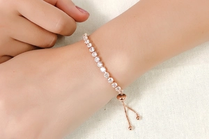 Close-up of rose gold tennis bracelet with round crystals on an adjustable slider clasp