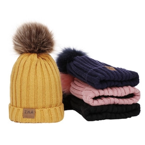 Detailed view of winter knit baby hats with large faux fur pom-poms in four vibrant colors