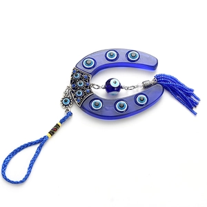 Close-up of Turkish evil eye horseshoe pendant with blue tassels and silver metal details