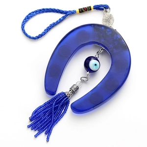 Detail of blue evil eye horseshoe amulet featuring a vibrant tassel and braided cord hanging