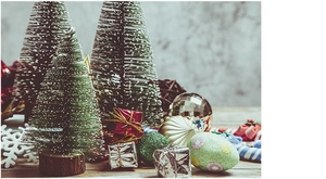 Mini white flocked Christmas trees with gift boxes and ornaments on a wooden base