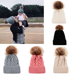 Macro view of cable knit pattern and large faux fur pompon on various colored beanies