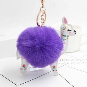 Detailed macro view of purple faux fur ball keychain with white alpaca charm and gold clasp