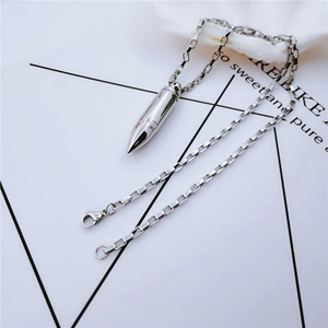 Vue détaillée d'un collier pendentif balle en acier inoxydable argenté sur carte déco
