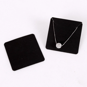 Black necklace display card with silver rhinestone ball pendant on white background