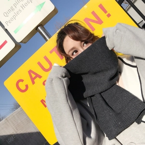 Detailed close-up of dark grey thick knit scarf texture worn in a chic winter street style