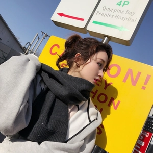 Detail of dark grey thick knit scarf texture worn by a model in outdoor lighting