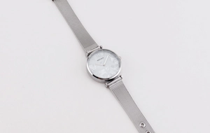 Detail shot of the silver mesh strap and white mother of pearl dial of the quartz watch