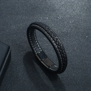 Braided black leather bracelet with magnetic stainless steel clasp on a textured surface