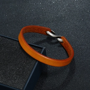 Close-up of vintage brown leather bracelet with metal hook clasp on textured black box