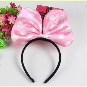 Close-up of a pink polka dot satin bow headband with a Sweet label on white background
