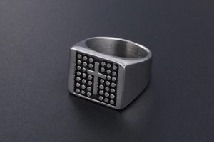 Macro shot of silver signet ring with embossed cross and black dotted texture detail
