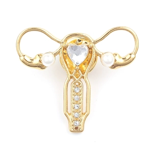Gold-tone uterus brooch with heart-shaped rhinestones and pearls on white background