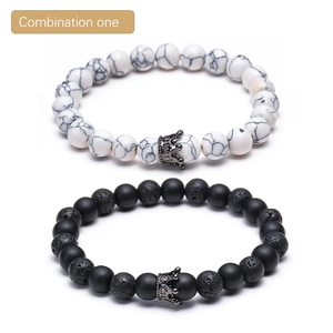 Detail view of white turquoise and black lava stone bead bracelets with crown charms