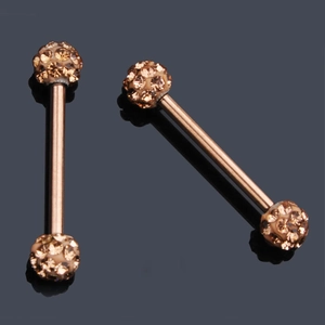 Macro view of rose gold nipple barbells with amber zircon spheres on a mirror surface