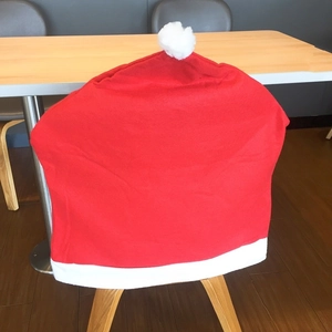 Detail of red Santa hat chair cover with white plush pompom for Christmas table decor