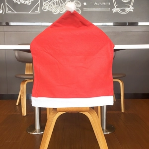 Close-up of red non-woven Santa hat chair cover with white pompom and plush trim