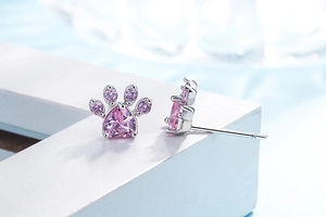 Close-up of cat paw stud earrings with pink heart zircon and polished silver finish