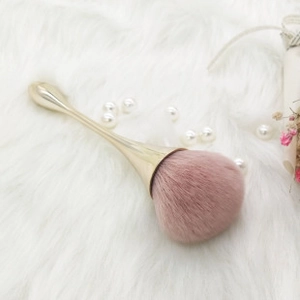 Pink makeup brush with golden mermaid handle on white plush background with pearls