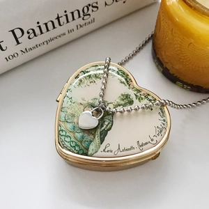 Close-up of minimalist silver heart pendant and ball chain on vintage heart gift box
