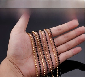 Detailed close-up of 2-3mm gold and black titanium steel bead chains on a hand