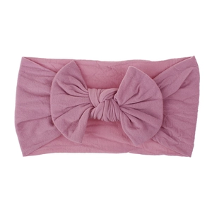 Dettaglio di una morbida fascia per neonati in nylon rosa antico con un grande fiocco