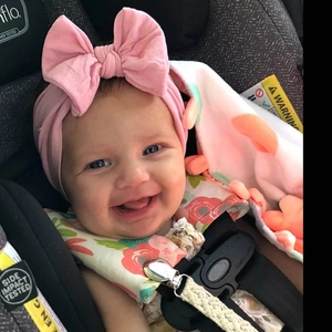 Primo piano di un bambino sorridente con una fascia per capelli con fiocco rosa