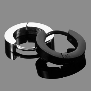 Macro shot of polished black and silver stainless steel hoop earrings on reflective surface