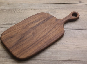 Detailed view of dark walnut wood grain and hanging hole on a rustic bread board